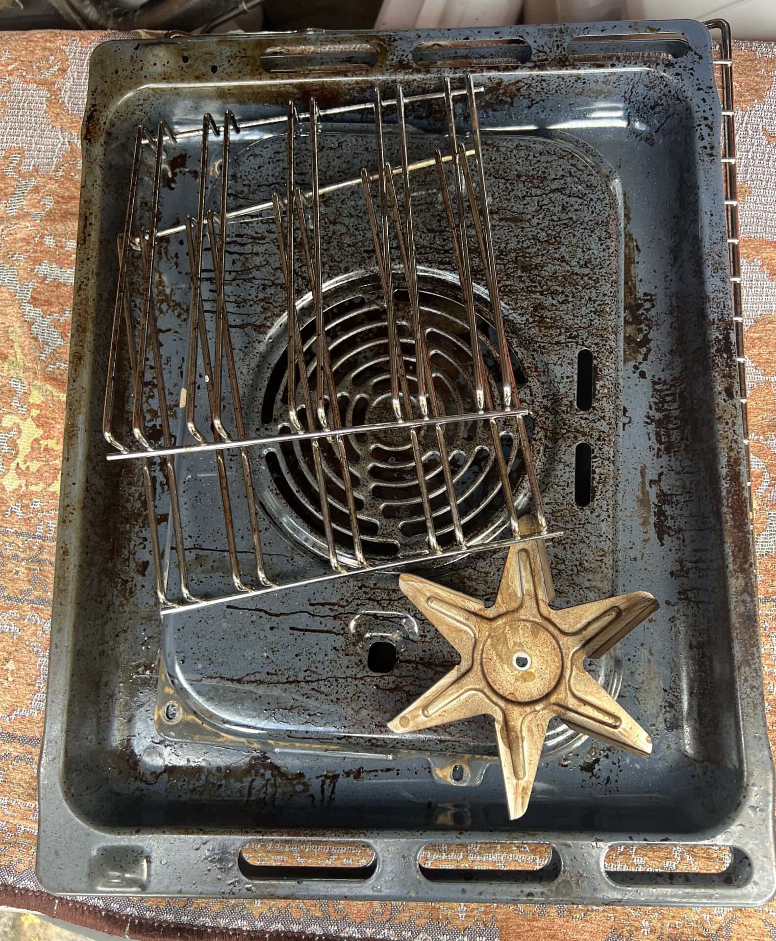 Greasy oven racks, trays, back plate and fan blade before cleaning in West Bromwich