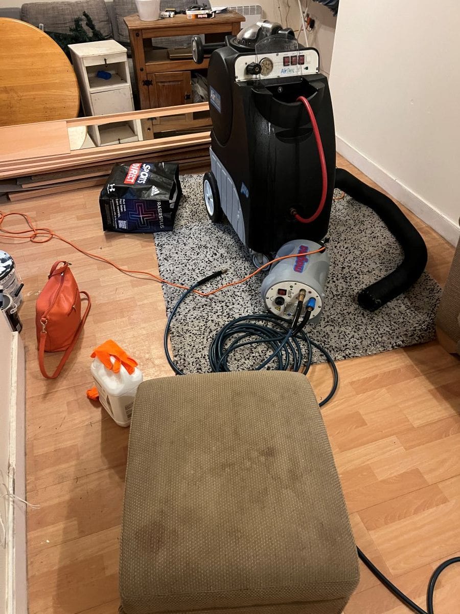 Marked fabric footstool beside professional upholstery cleaning equipment in Bearwood
